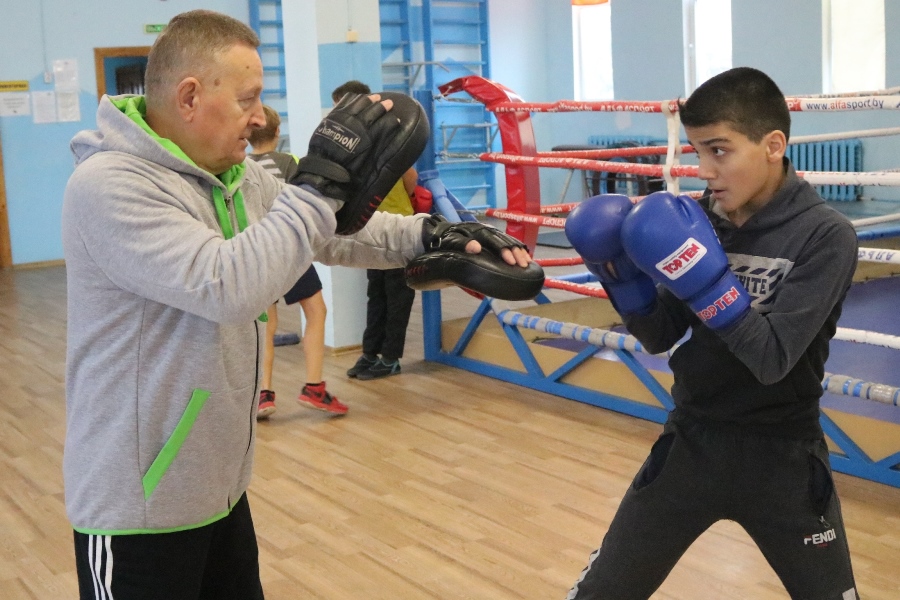 Professional boxing trainer demonstrating technique in modern gym